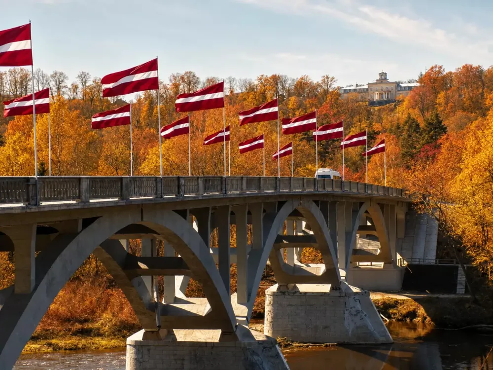 The Gauja Bridge in Sigulda with Latvian flags in an autumn landscape
