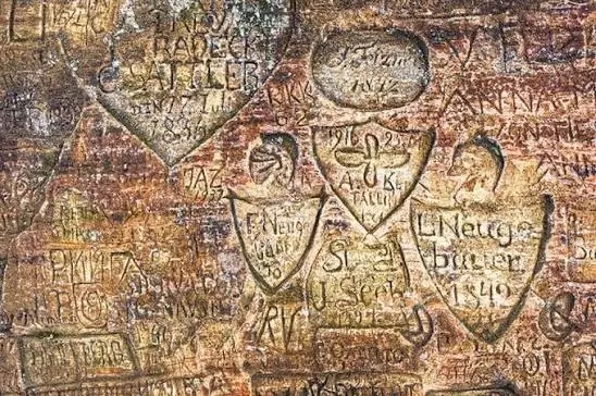 Ancient inscriptions and coats of arms carved into the sandstone wall of Gutmanis Cave